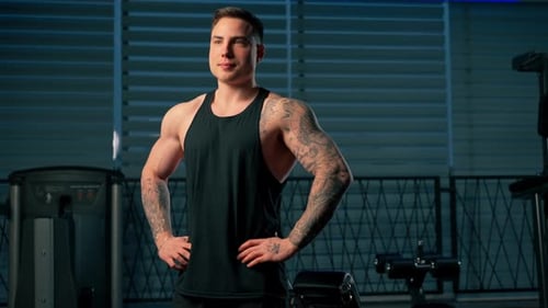 in the Gym Young Handsome Guy with Tattoos in a Black Tshirt Rests After Training