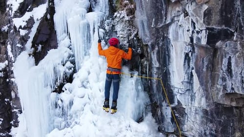 Ice Climber Ascending Frozen Waterfall in Winter