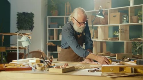 Senior Adult Woodworker Smoothing Wood in Studio