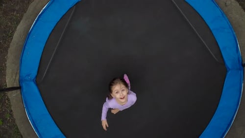 View of the Jumping Girl From the Drone A Little Girl is Jumping on a Trampoline in the Yard The
