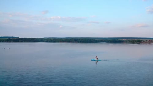 Man Paddleboarding on a Calm Lake, Aerial View