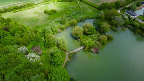 Aerial view of natural landscape with a river flowing among the village. Flying above the green fore