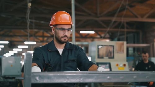 Metal pieces, standing. Man is working in the modern factory.