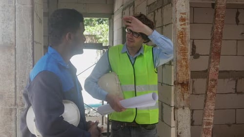 Construction Workers Discussing Plans Inside Building