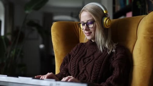 Woman Plays Keyboard While Wearing Headphones At Home