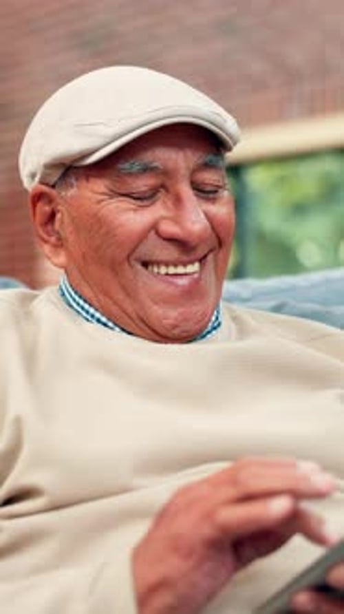 Smiling Senior Man Relaxing at Home With Tablet