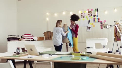 Young african american women design clothes together in a fashion startup studio