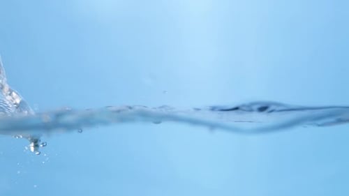 A single water drop falls into a smooth pool, creating perfect ripples. The motion highlights the pu