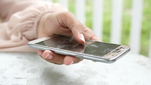 Hand Holds Damaged Cell Phone with Cracked Screen