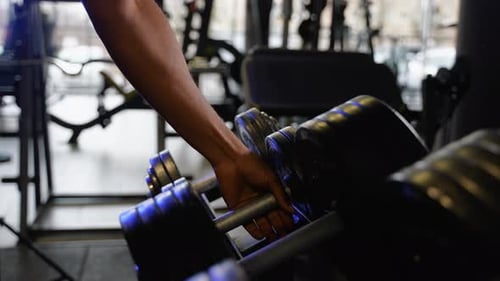 Close Up of Black Man Takes Dumbbell in Gym