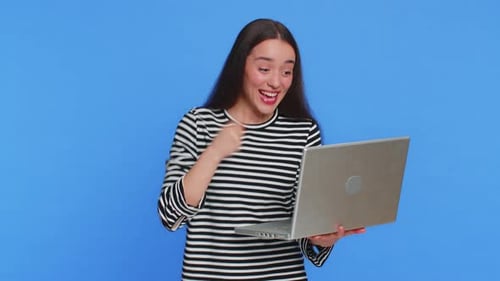 Excited Young Adult Woman Using a Laptop