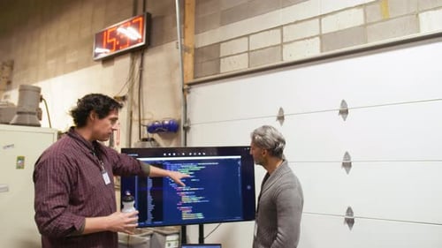 Computerprogrammierer diskutieren im Workshop über Computercode auf dem Gerätebildschirm