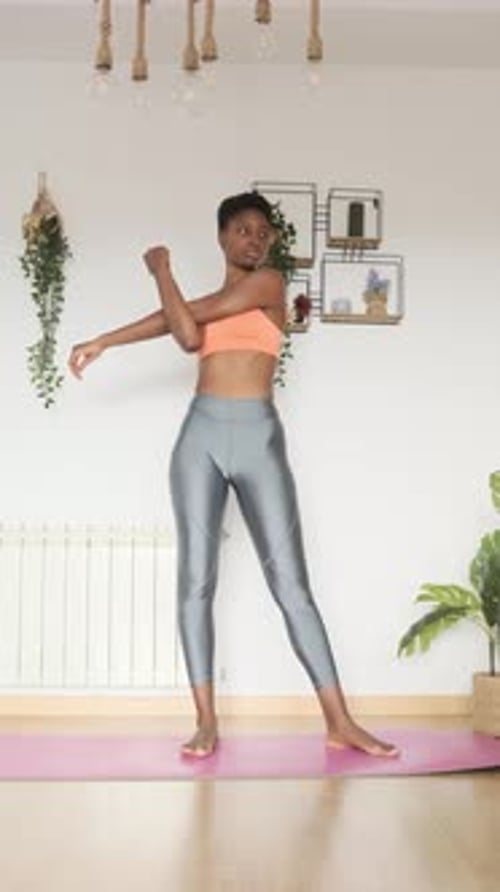 Mujer africana seria estirándose en casa