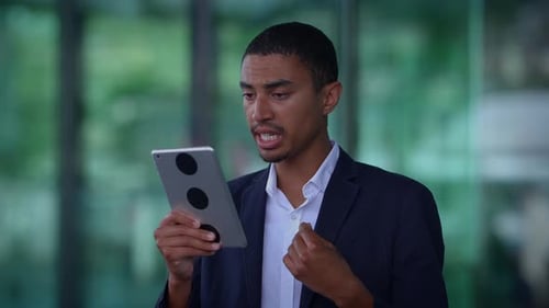 A Professional Man is Utilizing a Tablet Within a Modern Office Environment Effectively