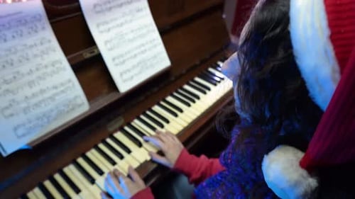 Woman Plays Piano Wearing a Santa Hat