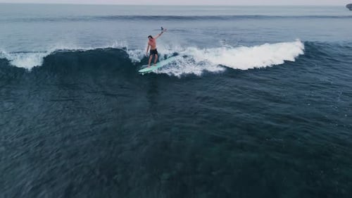 Surfer Rides on Surfboard on Small Ocean Wave Surfing Men Riding on Longboard Aerial View
