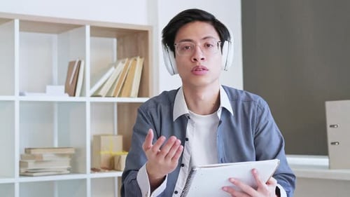 Young Adult Holding Notepad Talks to Camera