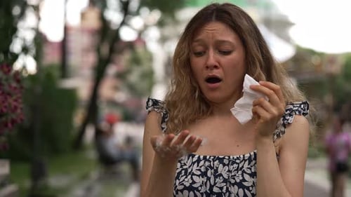 Woman Sneezing With Allergies in Urban Park