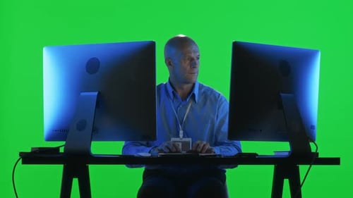 Data Center Specialist Working on Computer with Dual monitor on Green Wall