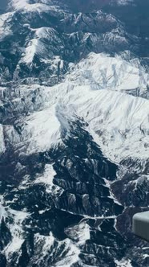 Airplane Flying Over Majestic Snowy Mountain Range
