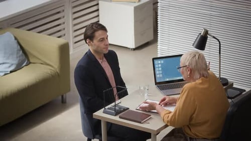 Junger männlicher Bewerber beantwortet Fragen während des Vorstellungsgesprächs in einem modernen Büro