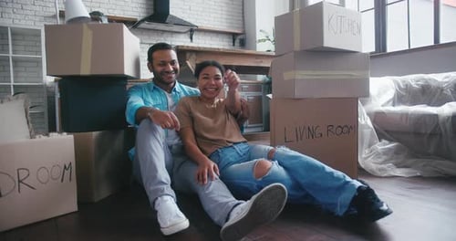 Married Couple Sitting Among Boxes Shows Key to New Flat