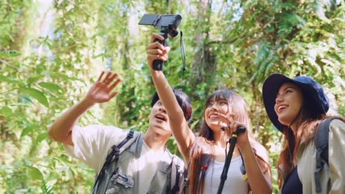 Grupo de vloggers mochileiros asiáticos se diverte viajando juntos pela floresta.