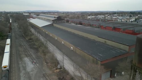Aerial drone view of a train traveling through a massive industrial facility.