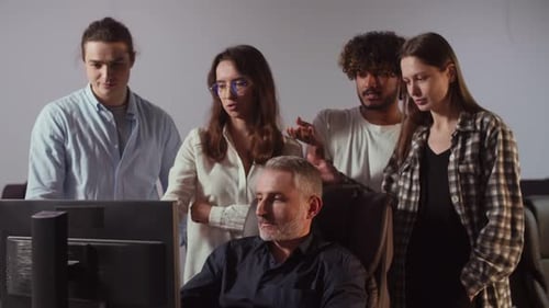 Office Workers Help Their Colleague Solve Computer Problems A Group of People is Looking at