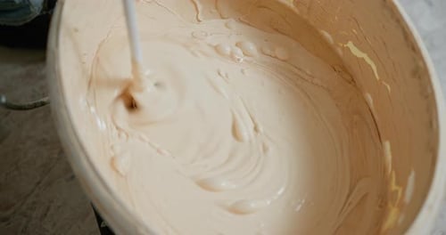 Creamy White Substance Being Mixed in Bucket
