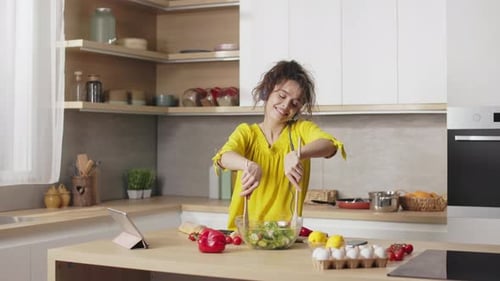 Woman Cooking Salad and Listening to Music
