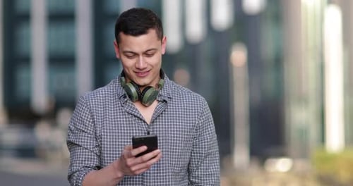 Young adult male with smartphone in city