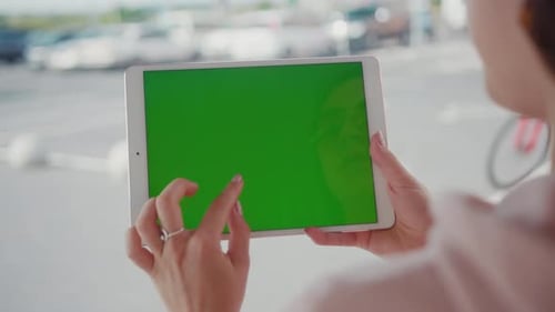 Over the Shoulder View Young Woman Using Digital Tablet Greenscreen Mockup Technology in the City at