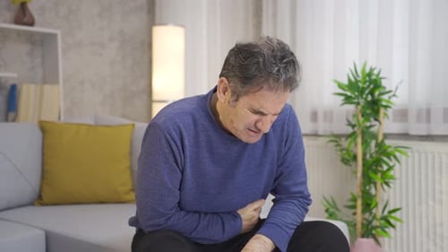 Mature man with stomach ache suffering at home.
