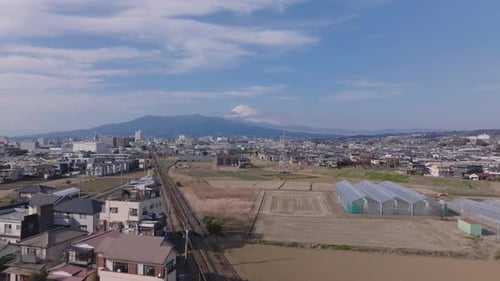 Forwards Fly Above Train Line and Buildings in Town Large Greenhouses on Bank of River Mountains