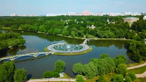 Island with bridges and fountains in city pond. Beautiful fountain complex on river island