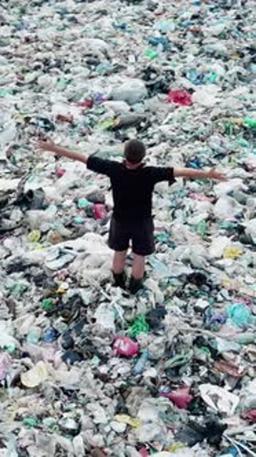 Standing in Garbage Landfill with Raised Arms