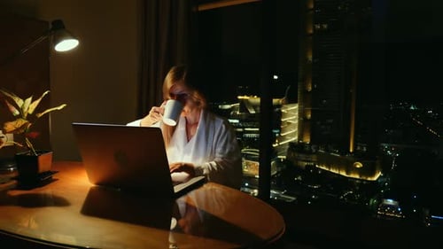Femme concentrée travaillant sur un ordinateur portable la nuit avec les toits de la ville en arrière-plan Équilibre entre vie professionnelle et vie privée