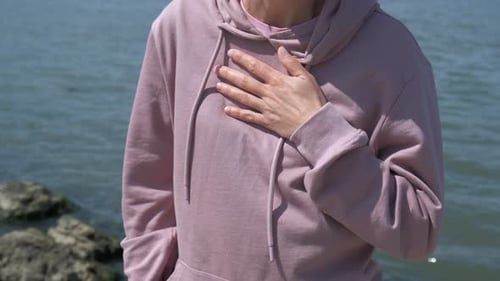 Woman Holding Inhaler by the Ocean on Sunny Day