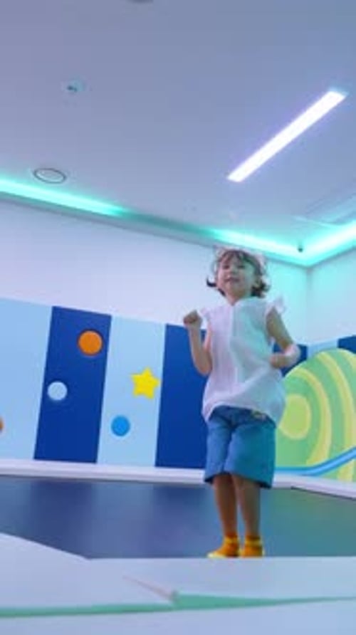 Happy Girl Jumping on a Trampoline Indoors