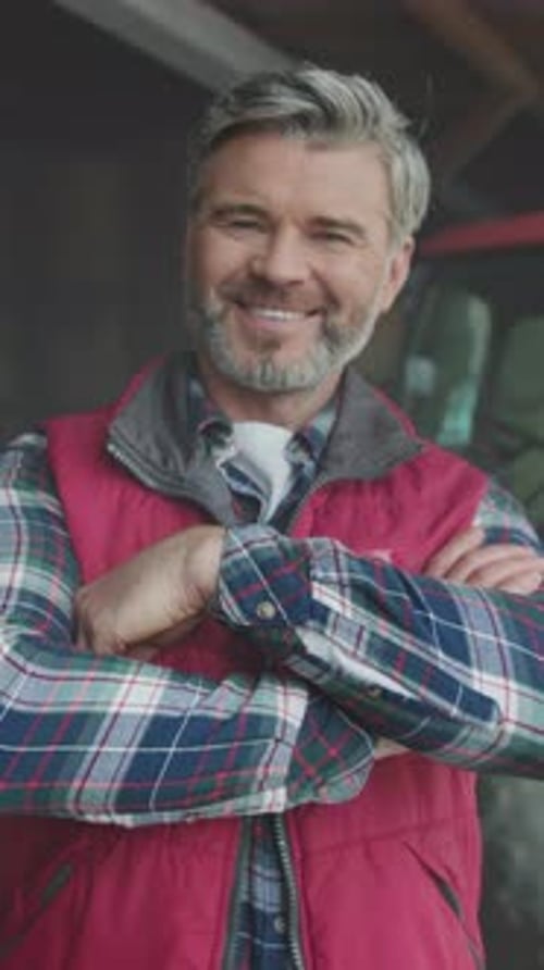 Smiling Man in Vest Poses near Red Tractor