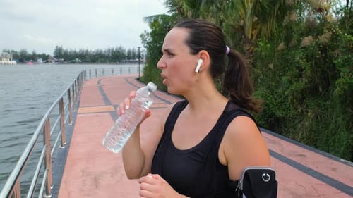 Woman Drinking Water After Exercise Near Tropical Water