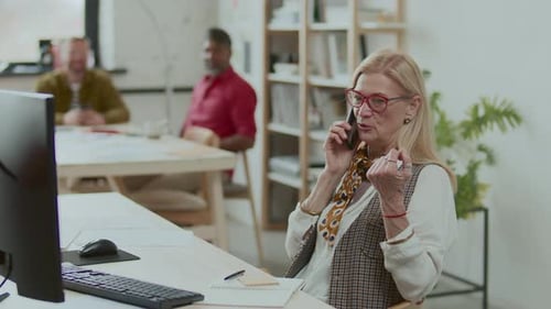 Senior Businesswoman Talking on Mobile Phone at Desk in Modern Office