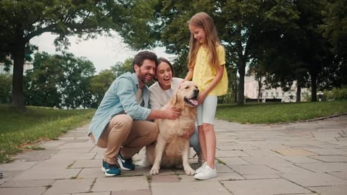 Happy Family Petting Golden Retriever Dog in Park