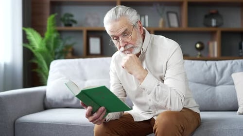Man Reading Book on Couch Indoors