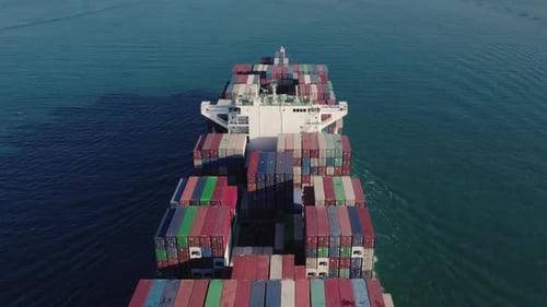 Aerial top view of a loaded container cargo vessel traveling over ocean.