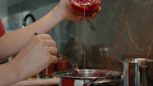 Make homemade raspberry jam by boiling fresh raspberries in the kitchen