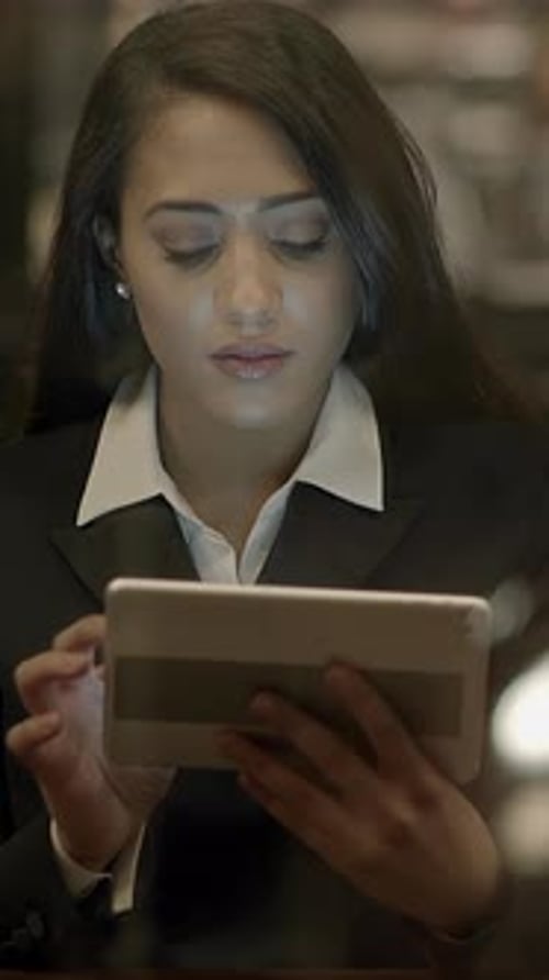 A Professional Woman is Utilizing a Tablet for Work in a Modern Office Environment Today