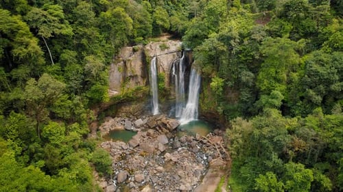 Aerial view of multiple waterfalls surrounded by dense green rainforest