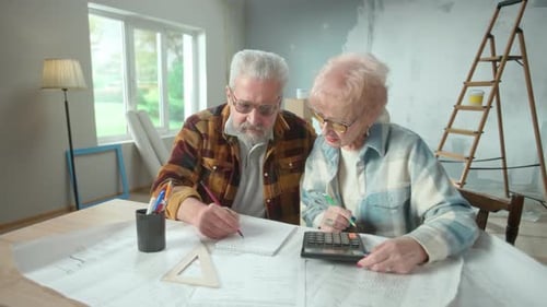 Elderly Man and Woman are Calculating Expenses of Repairing an Apartment on Calculator